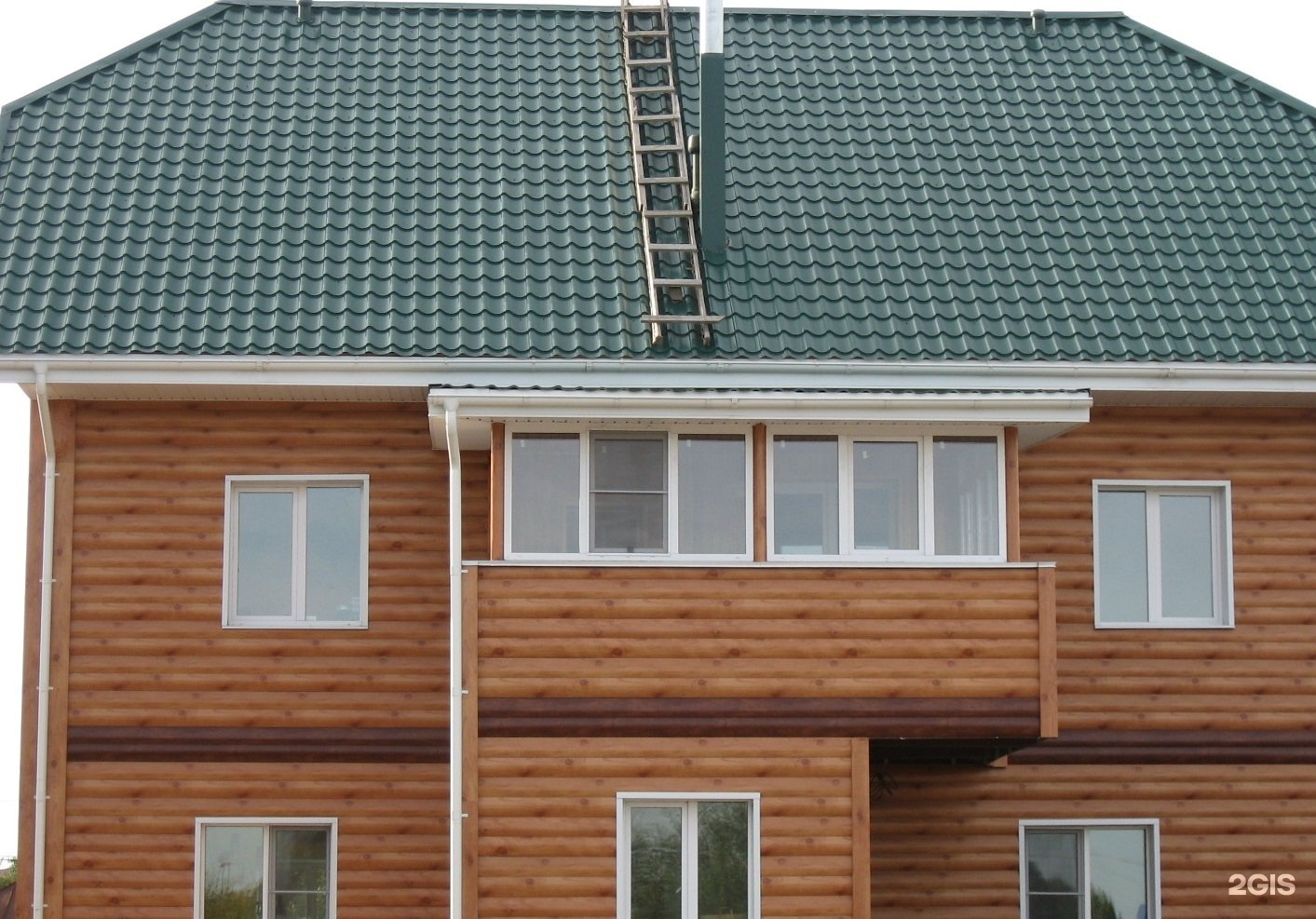 Брусовой дом с зеленой крышей